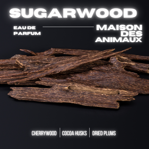 A pile of dark brown woody pieces on a black background, presenting Sugarwood eau de parfum by Maison des Animaux with scent notes of Cherrywood, Cocoa Husks, and Dried Plums.
